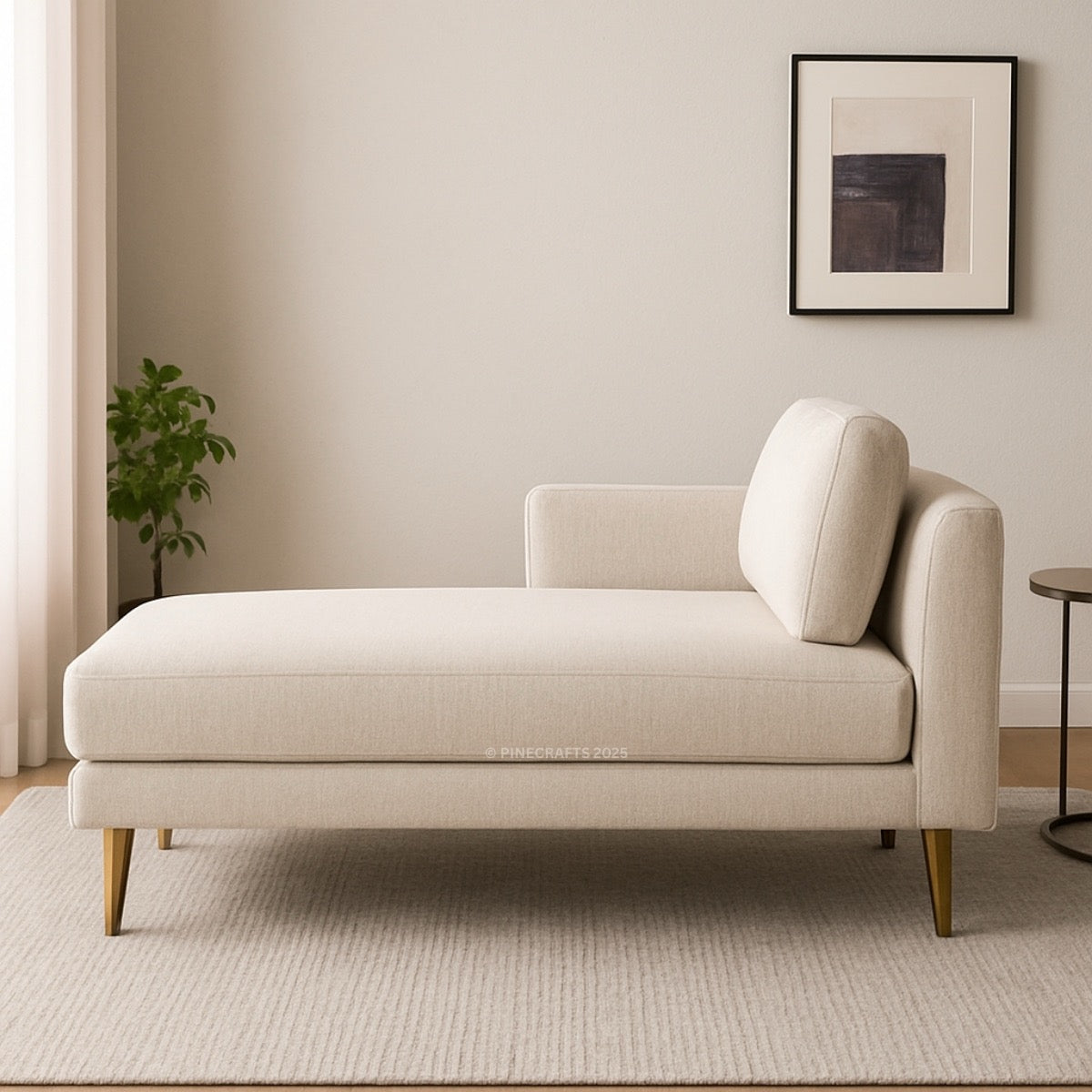 Beige chaise lounge in a room with a plant and framed picture on the wall.